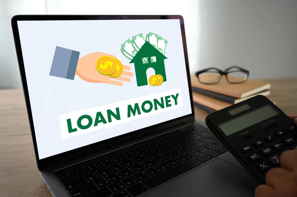 Laptop con la palabra "LOAN MONEY" y un gráfico, ilustrando los mitos financieros.