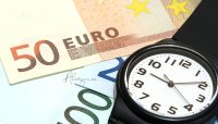 Un reloj y billetes de euro, representando la pobreza de tiempo.