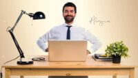 Hombre sentado correctamente frente a un ordenador portátil, ilustrando una postura ergonómica para cuidar la espalda y la vista.
