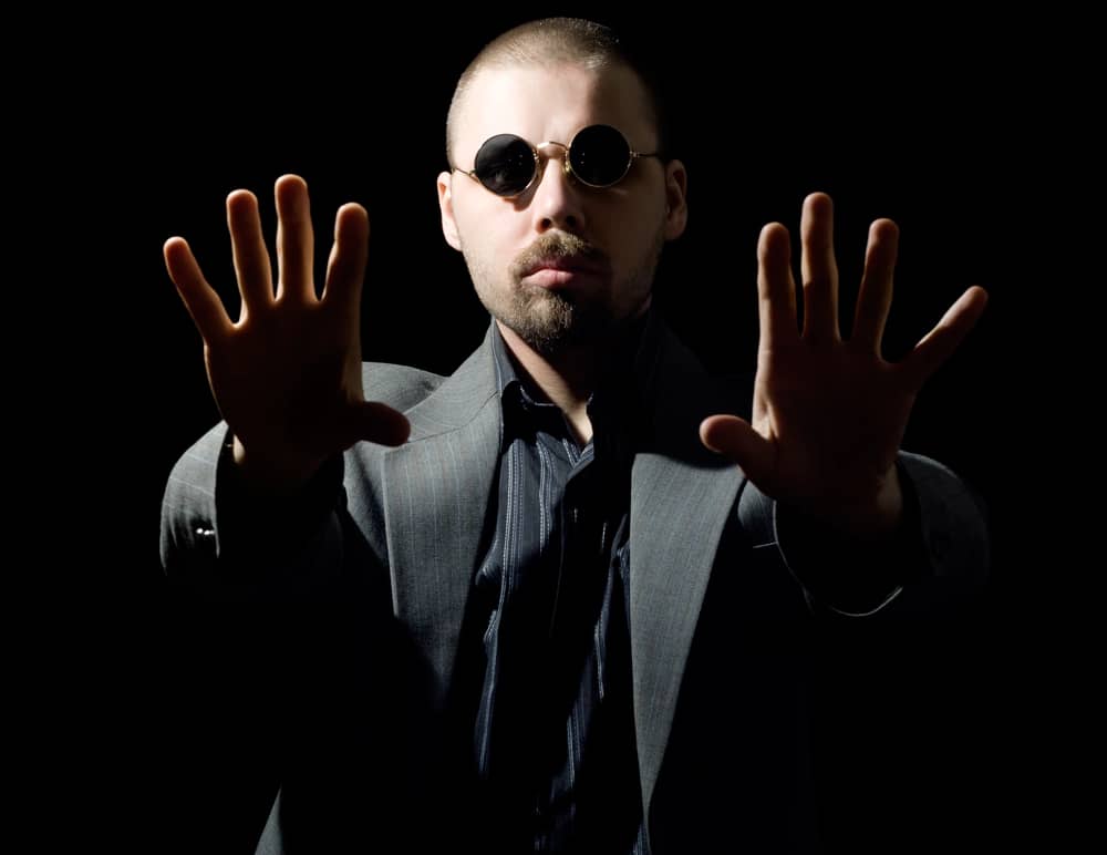 Hombre con gafas de sol y traje gesticulando, representando sesgo de la ilusión de control