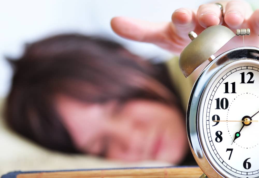 Persona apagando un despertador por la mañana, un gesto clave para el hábito de despertarse temprano y mejorar la productividad.
